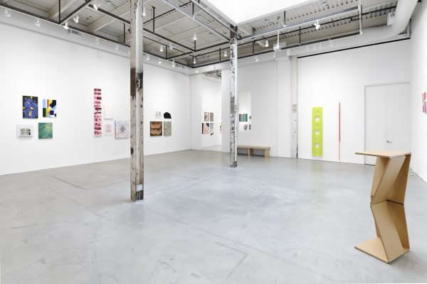 Installation view showing paintings on the walls and a sculpture on the right side of the image